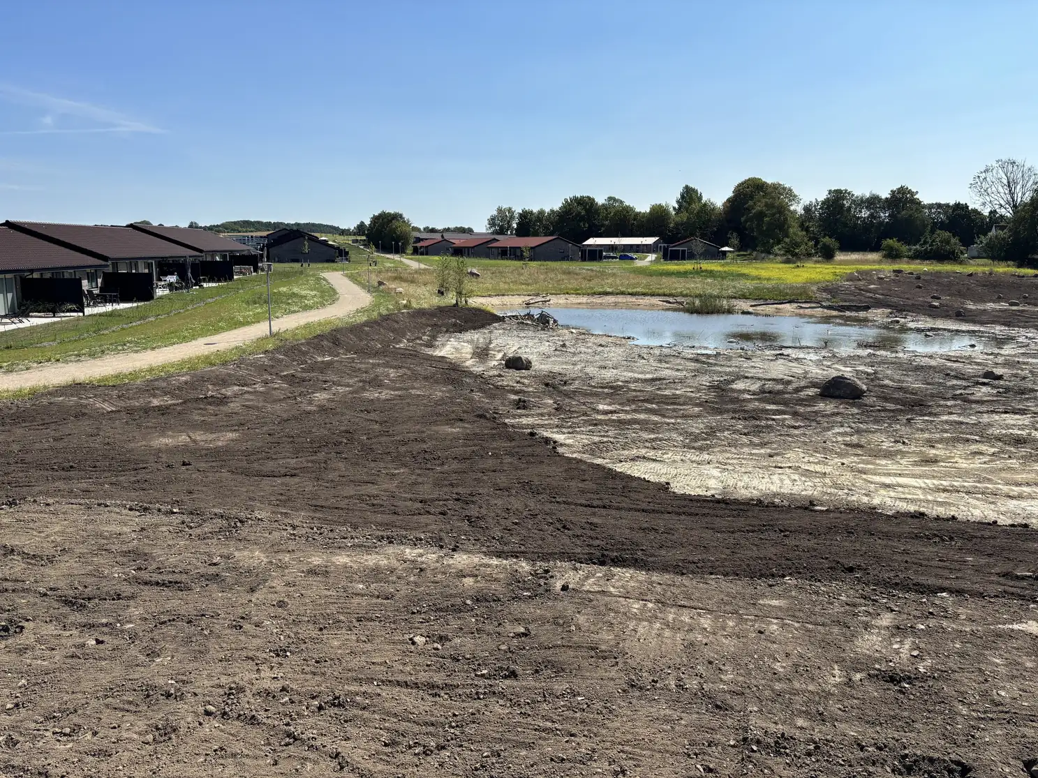 Udgravning og planering af jord ved et vandhul